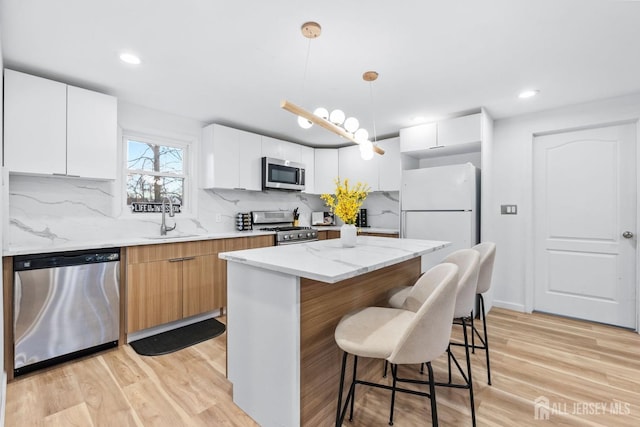 kitchen with light wood finished floors, a breakfast bar area, appliances with stainless steel finishes, and a sink