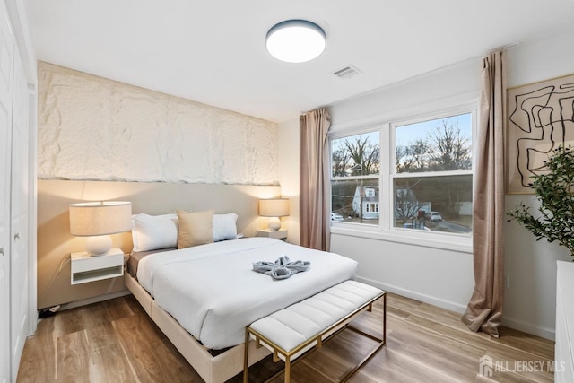 bedroom with visible vents, baseboards, and wood finished floors