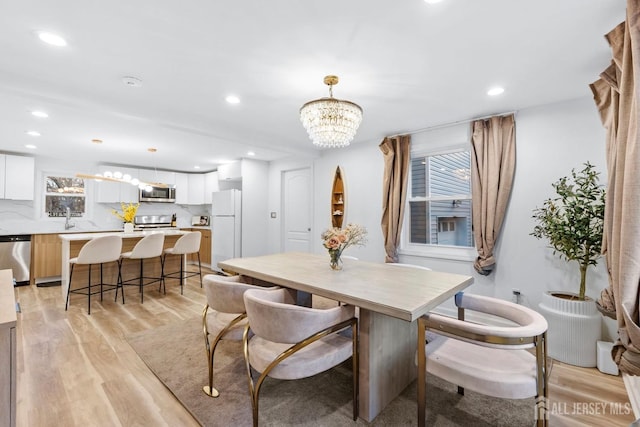 dining room featuring light wood-type flooring, an inviting chandelier, and recessed lighting