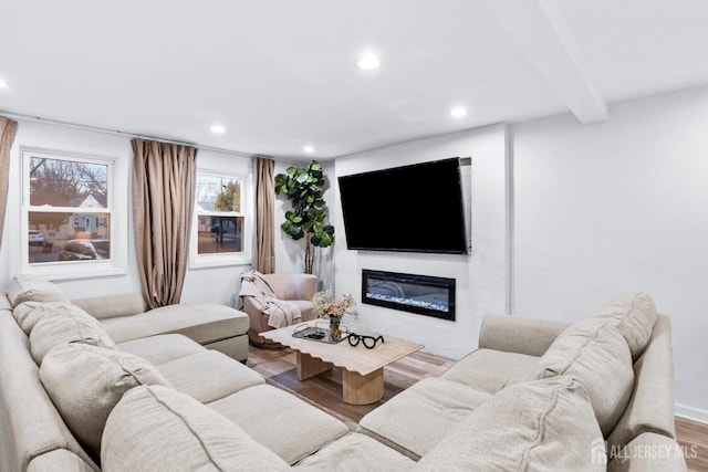 living area with a glass covered fireplace, beamed ceiling, recessed lighting, and wood finished floors