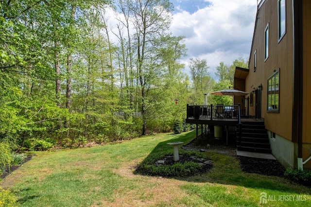 view of green lawn featuring stairs and a deck