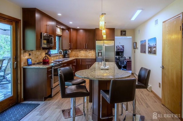 kitchen featuring appliances with stainless steel finishes, light wood-type flooring, a sink, healthy amount of natural light, and recessed lighting