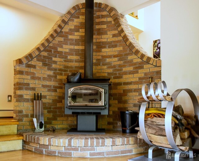 detailed view of a wood stove, a baseboard heating unit, and wood finished floors