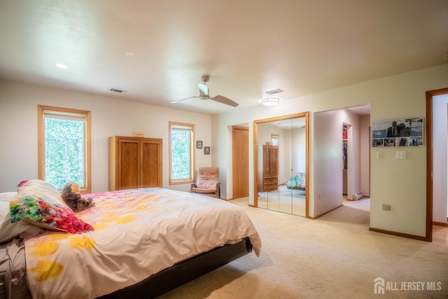 bedroom with multiple windows, light colored carpet, and ceiling fan