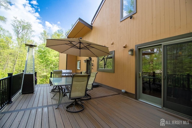 wooden deck with outdoor dining space and area for grilling