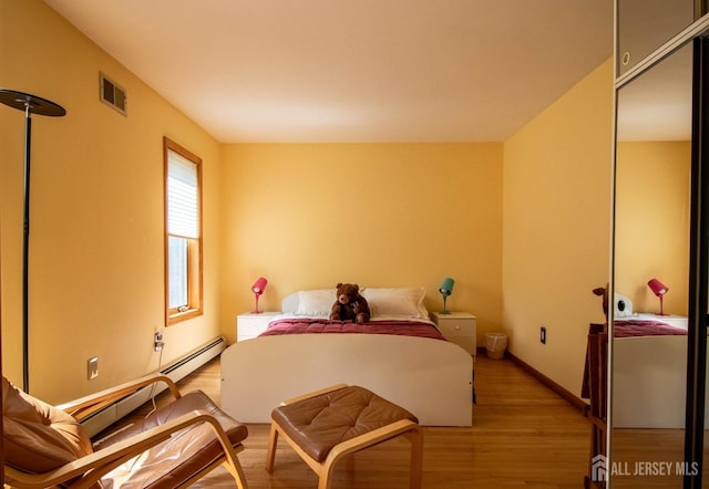 bedroom featuring light wood finished floors, a baseboard radiator, baseboards, and a closet