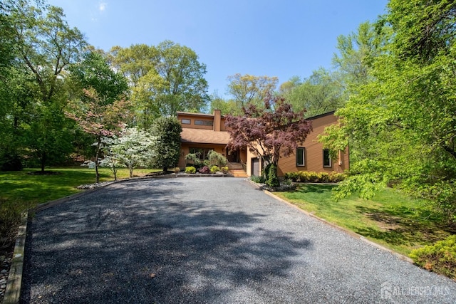 view of front facade featuring asphalt driveway and a front yard