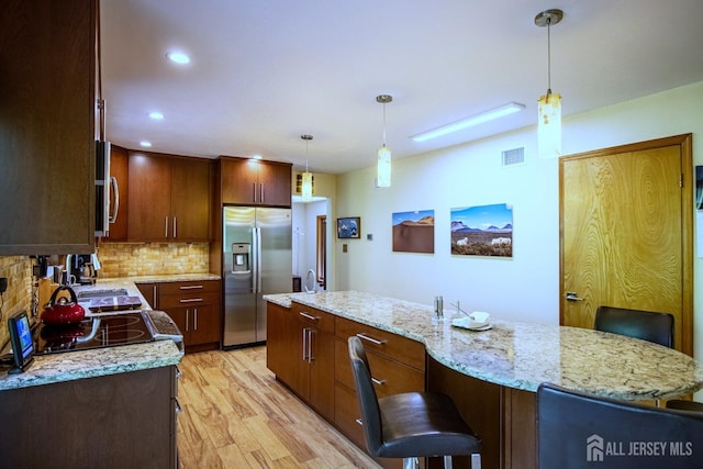 kitchen featuring appliances with stainless steel finishes, light wood-type flooring, tasteful backsplash, hanging light fixtures, and recessed lighting