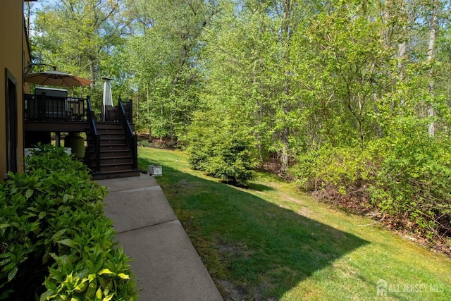 view of grassy yard with stairs and a wooden deck