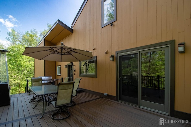 wooden terrace featuring outdoor dining space and area for grilling
