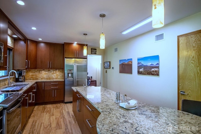 kitchen featuring stainless steel refrigerator with ice dispenser, a sink, electric stove, light stone countertops, and decorative backsplash
