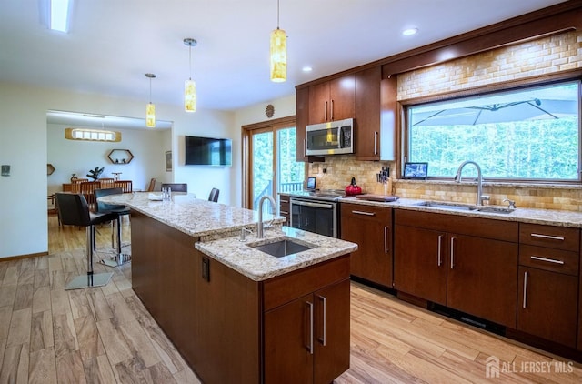 kitchen with appliances with stainless steel finishes, a sink, tasteful backsplash, a center island with sink, and recessed lighting