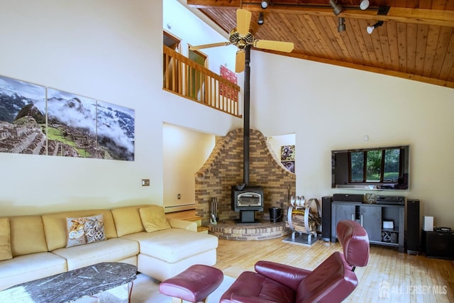 living area with high vaulted ceiling, wooden ceiling, a wood stove, wood finished floors, and ceiling fan