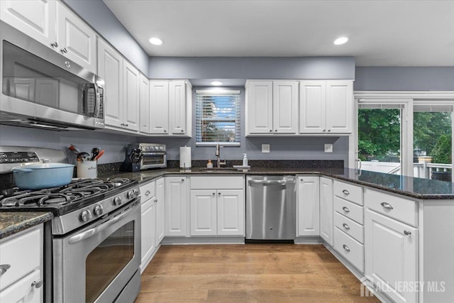 606 Hayward St, Bound Brook, NJ 08805 - kitchen featuring appliances with stainless steel finishes, white cabinets, a peninsula, recessed lighting, and light wood finished floors