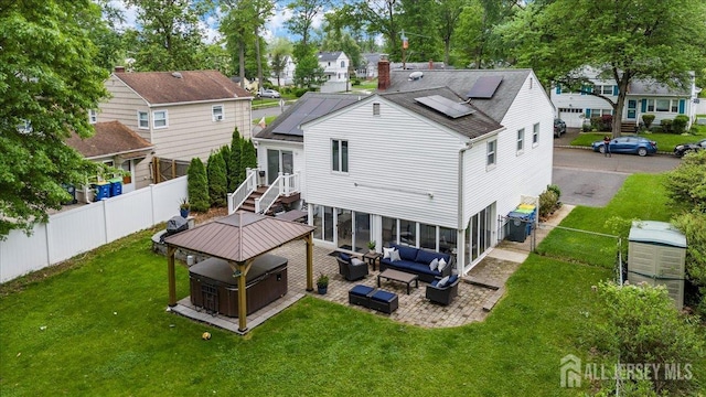 606 Hayward St, Bound Brook, NJ 08805 - rear view of property with a hot tub, an outdoor living space, a fenced backyard, and solar panels