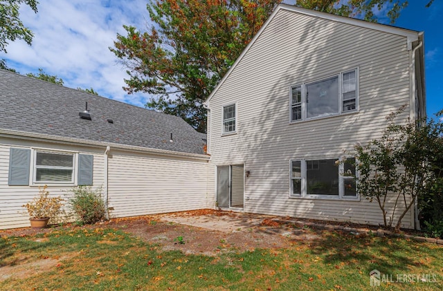 back of house featuring a lawn and a shingled roof