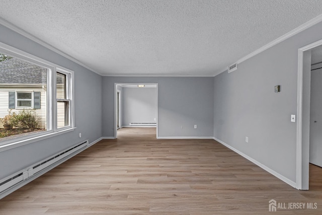 spare room with baseboard heating, light wood-style flooring, crown molding, and visible vents