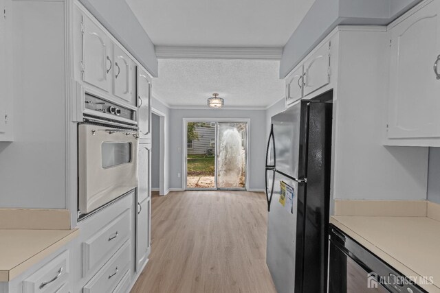 kitchen with black fridge, stainless steel oven, white cabinetry, and light hardwood / wood-style floors