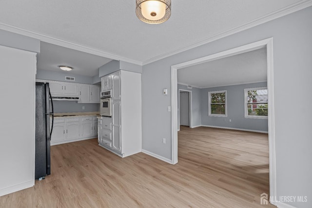 kitchen with visible vents, freestanding refrigerator, ornamental molding, oven, and white cabinets