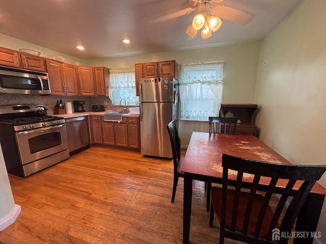 64 Bender Ave, Iselin, NJ 08830 - kitchen with appliances with stainless steel finishes, light wood-type flooring, ceiling fan, tasteful backsplash, and light countertops
