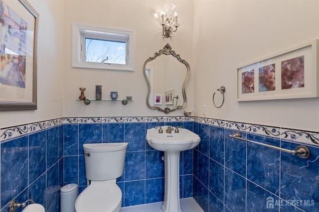 bathroom featuring a wainscoted wall, toilet, and tile walls