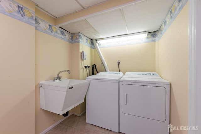 laundry area featuring light tile patterned floors, a sink, and washer and dryer