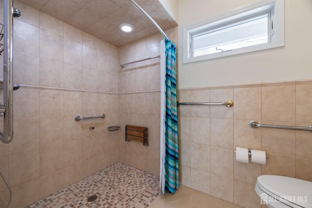 bathroom with tile walls, a shower stall, and toilet