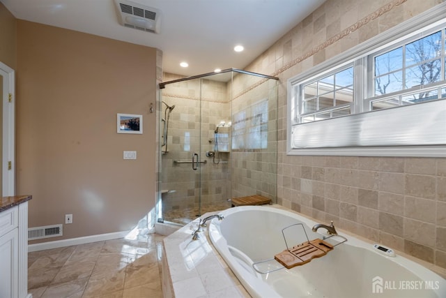 bathroom with a garden tub, plenty of natural light, and visible vents