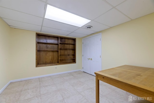 interior space with a drop ceiling and baseboards