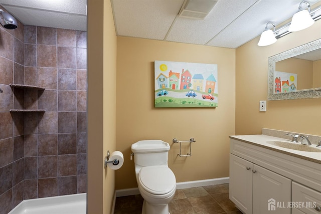 full bathroom featuring toilet, a tile shower, vanity, tile patterned flooring, and baseboards