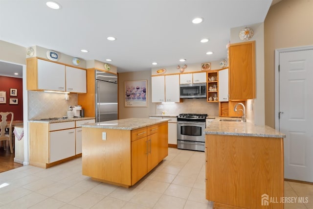 kitchen with appliances with stainless steel finishes, a sink, white cabinetry, and a center island