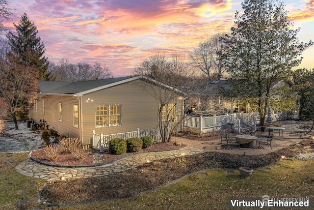 property exterior at dusk with cooling unit, a patio, and fence