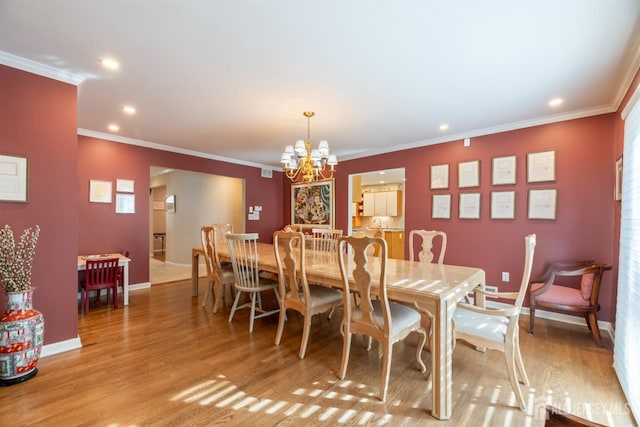 dining space featuring baseboards, ornamental molding, light wood-style floors, a notable chandelier, and recessed lighting