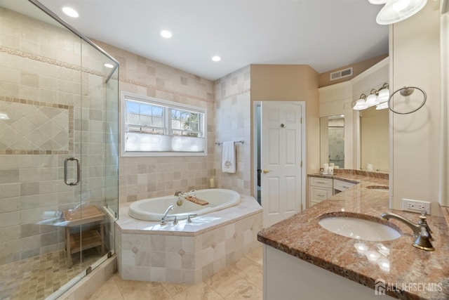 bathroom with a stall shower, visible vents, a sink, a garden tub, and two vanities