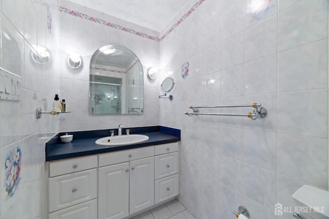 full bathroom featuring tile patterned floors, vanity, tile walls, and a shower stall