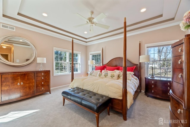 bedroom featuring a tray ceiling, visible vents, light carpet, and multiple windows