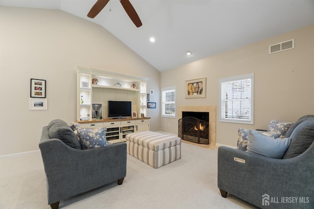 living area featuring a healthy amount of sunlight, visible vents, vaulted ceiling, and light colored carpet