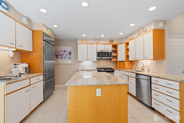 kitchen featuring white cabinetry, stainless steel appliances, a sink, and a center island