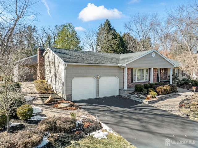 view of front of home featuring a shingled roof, driveway, a chimney, and an attached garage