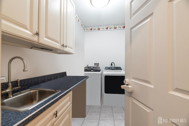 clothes washing area featuring light tile patterned floors, washing machine and dryer, cabinet space, and a sink