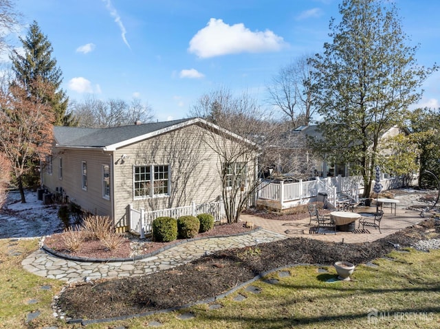 view of side of property with central air condition unit, a yard, fence, and a patio