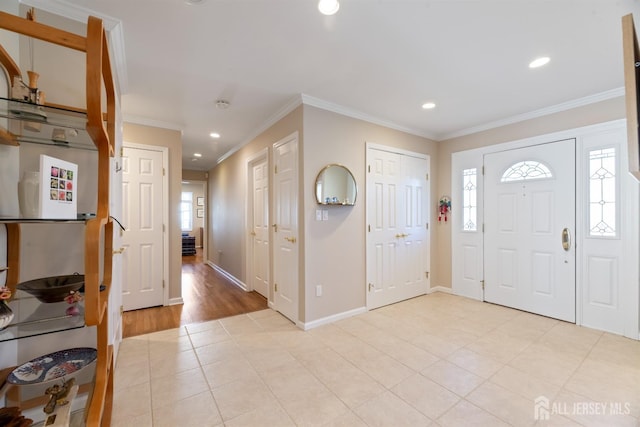 foyer entrance with a wealth of natural light, light tile patterned flooring, crown molding, and baseboards