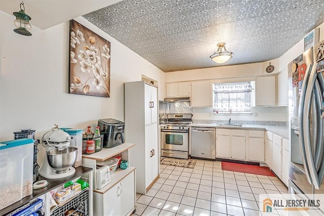 kitchen featuring sink, white cabinetry, light tile patterned floors, stainless steel appliances, and backsplash