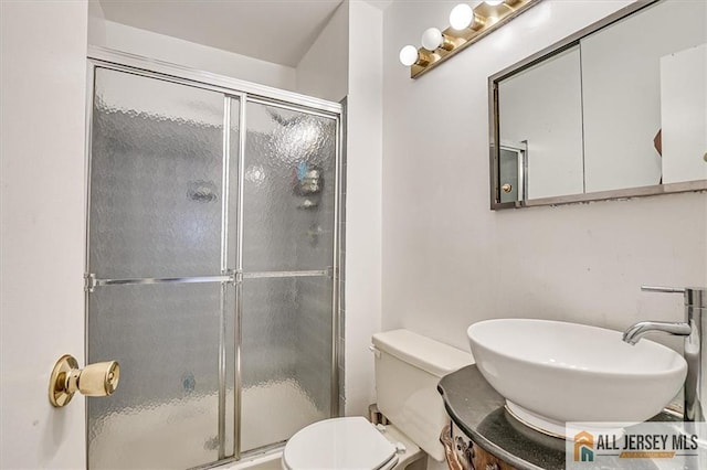 bathroom featuring vanity, a shower with shower door, and toilet