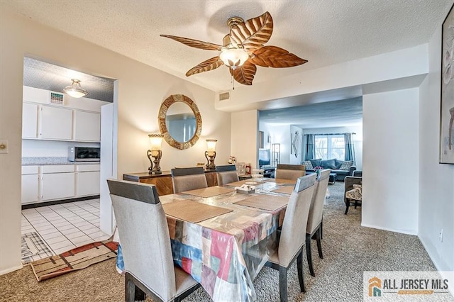 carpeted dining room featuring ceiling fan and a textured ceiling