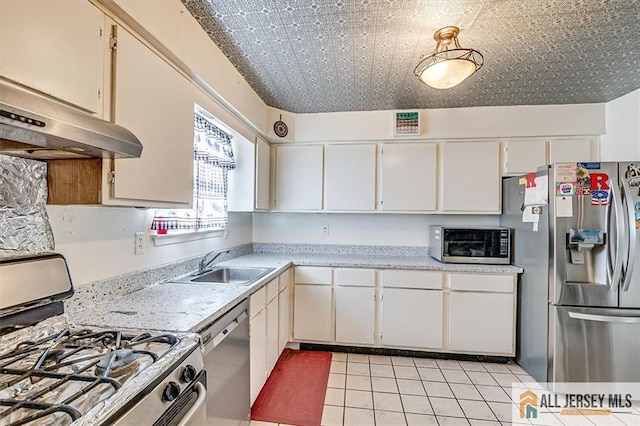 kitchen with sink, light tile patterned flooring, white cabinets, and appliances with stainless steel finishes