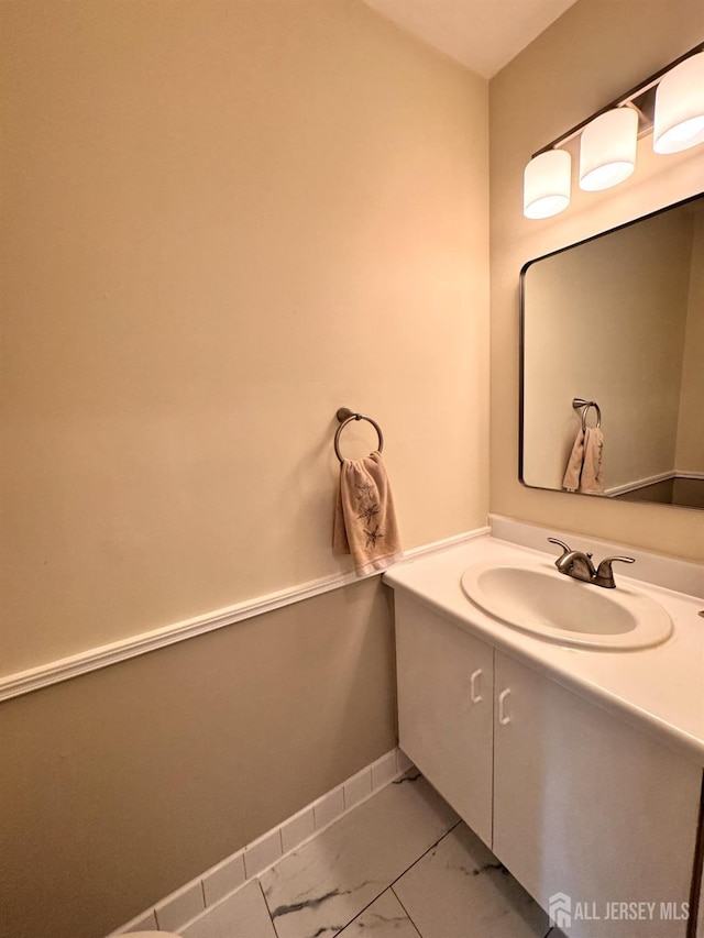 bathroom with baseboards, vanity, and marble finish floor