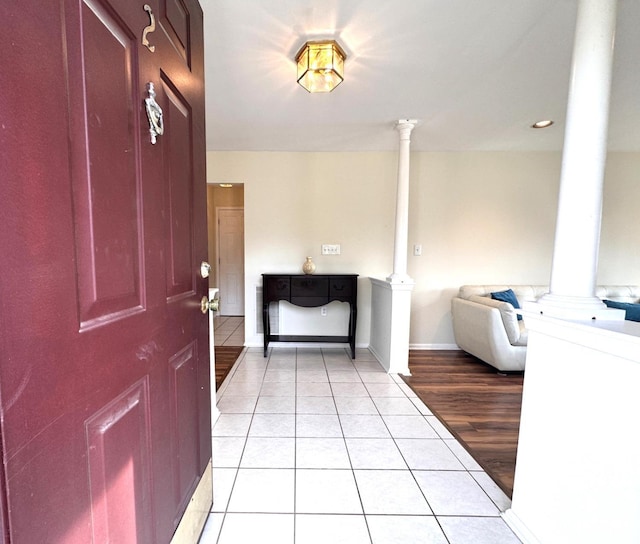 foyer entrance featuring baseboards, decorative columns, and light tile patterned floors