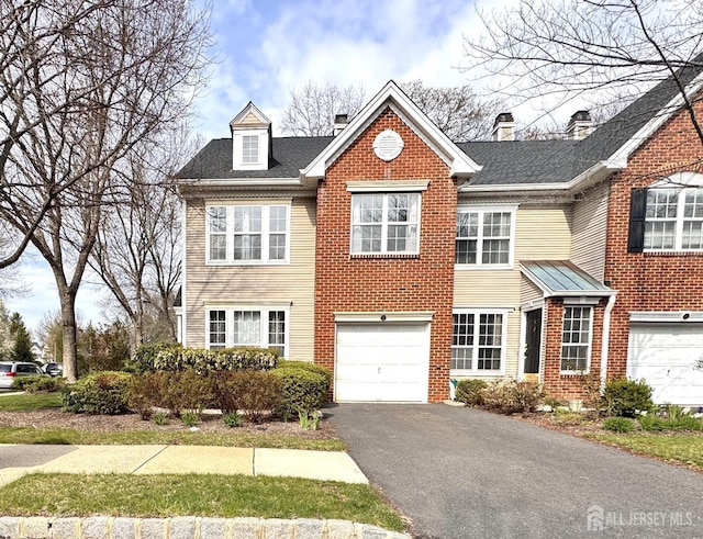 view of front of home with an attached garage, driveway, and brick siding
