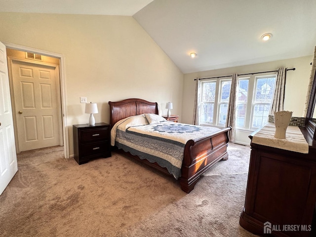 bedroom featuring light colored carpet, vaulted ceiling, and visible vents